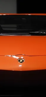 Front view of a vibrant orange sports car in a dark setting.