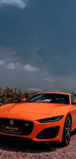 Vibrant orange sports car under cloudy sky.