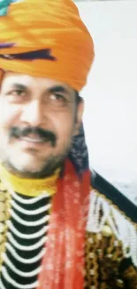 Man wearing a vibrant orange turban in traditional attire, smiling.