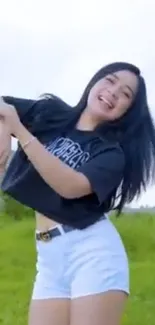 Woman joyfully dancing outdoors with a bright sky and green grass backdrop.