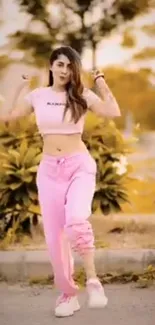 Woman dancing in pink outfit outdoors against a warm yellow background.