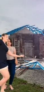 Two women dancing by a gray and blue construction site.