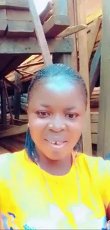 Smiling person in an orange shirt at a rustic lumberyard setting.