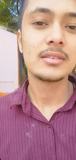 Vibrant portrait of a young man outdoors in a casual maroon shirt.