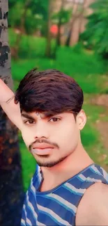 Young man posing outdoors with a green background.