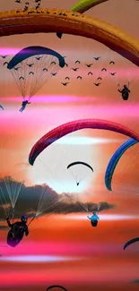 Colorful paragliders in a vibrant pink and orange sunset sky.