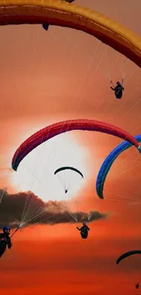 Paragliders soar across a vibrant orange sunset sky.