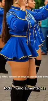 Dancers in vibrant blue uniforms perform.