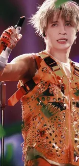 Vibrant performer in orange attire on stage, dynamic expression.