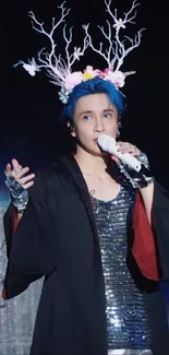 Performer with antlers and blue hair onstage.