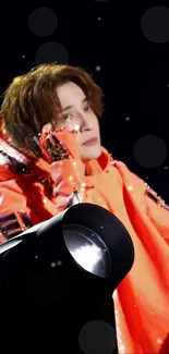 Performer in bright orange outfit with spotlight.