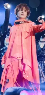 Performer in pink outfit on stage under bright lights.