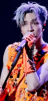 Dynamic performer in vibrant orange outfit on stage.