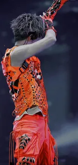 Performer in vibrant orange outfit on stage.