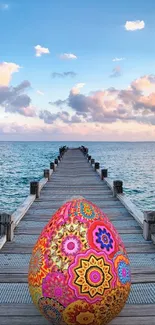 Vibrant decorative egg on a pier with ocean view.