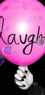 A pink balloon with 'laugh' text on a black background.