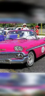 Pink classic car parked in sunny setting.