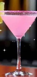 A vibrant pink cocktail in a martini glass with a lime wedge on a bar counter.