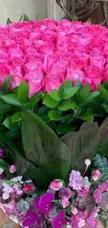 Vibrant pink rose bouquet with lush green leaves and mixed floral accents.