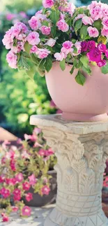 Elegant pink flowers on a stone pedestal in a vibrant garden setting.