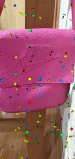 Hot pink leather bag hanging on a wooden chair.