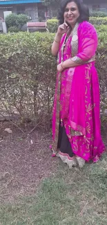 Woman in pink saree standing in garden, showcasing cultural fashion.