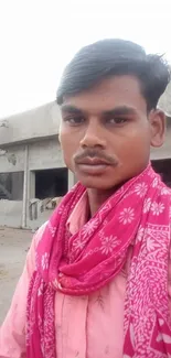 Man in vibrant pink scarf standing outdoors.