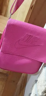 Vibrant pink leather shoulder bag with embossed logo.