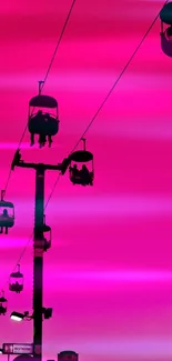 Silhouette of cable cars against vibrant pink sky.