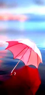 Pink umbrella floating on calm water reflecting a dreamy sky.