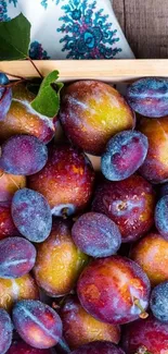 Vibrant plums in a rustic wooden crate, accented with leaves.