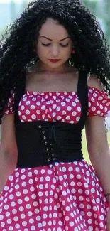 Woman in red polka dot dress with long curly hair.