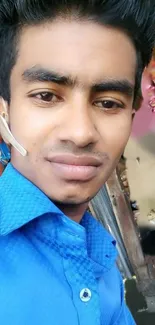 Portrait of a young man in blue shirt, vibrant background.