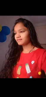 Vibrant portrait of girl in red shirt with balloons in background.