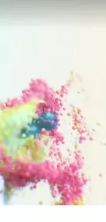 A vibrant explosion of pink, yellow, and blue powder on a white background.