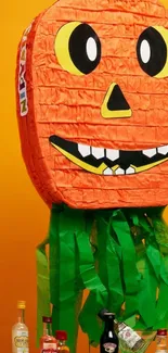 Festive orange pumpkin piñata with green streamers against a yellow background.