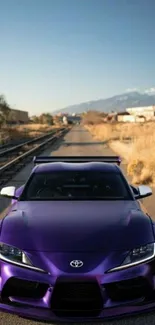 Purple sports car on a deserted road with clear sky.