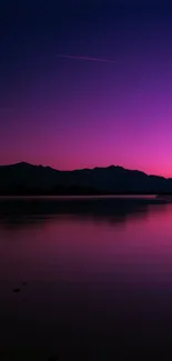 Vibrant purple sunset over tranquil waters with a scenic mountain silhouette.