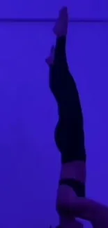 Silhouette of a person doing a headstand against a deep purple background.