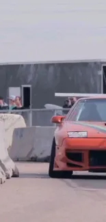 Orange drift car on speedway track, captured in action.