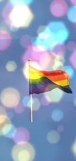 Vibrant rainbow flag against a blue sky with bokeh effect.