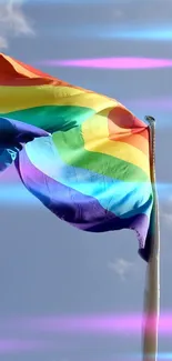 Rainbow flag waves against a bright blue sky wallpaper.