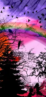 Colorful wallpaper of rainbow over silhouetted trees with birds.