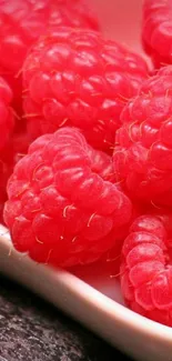 Close-up of red raspberries on a white plate for mobile wallpaper.