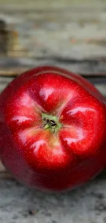 Vibrant red apple on rustic wooden surface wallpaper image.