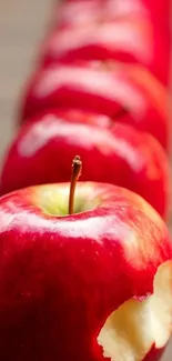 Lineup of vibrant red apples with a bitten apple in focus.