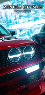 Close-up of a red car with headlights in an urban setting.