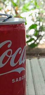 Red cola can with a lush green outdoor background.