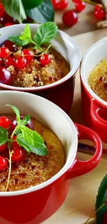 Red ceramic dishes with desserts topped with berries and green leaves.