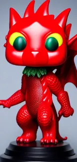 Red dragon toy with green eyes on a dark base and blue background.